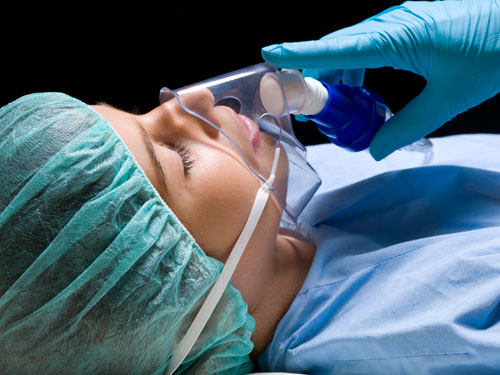 General anesthesia sedation: gloved hand holds breathing mask to sleeping patient's face Placentia, CA