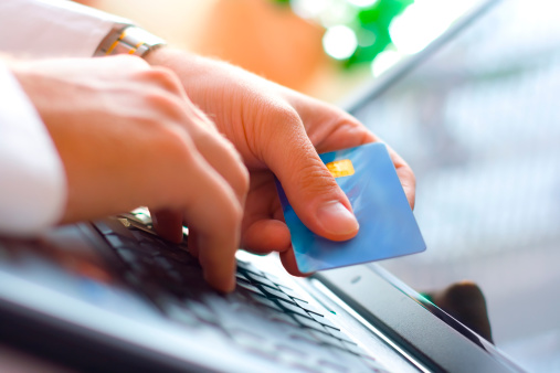 Image of hands holding a credit card and making a payment online Image of hands holding a credit card and making a payment online